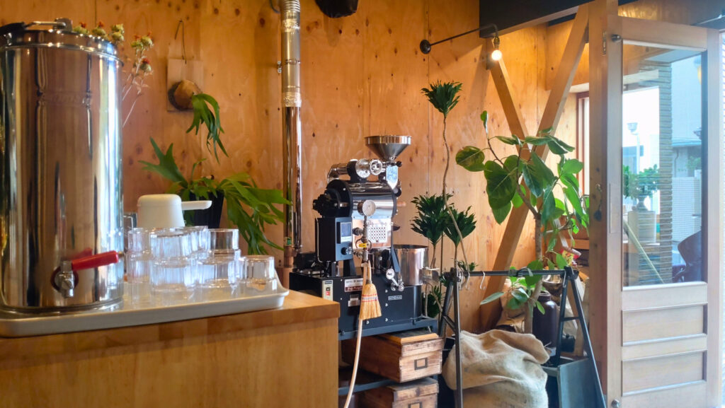 Hive Coffeeの店内入口。焙煎機とグリーンが迎えてくれる、おしゃれな雰囲気のカフェ空間