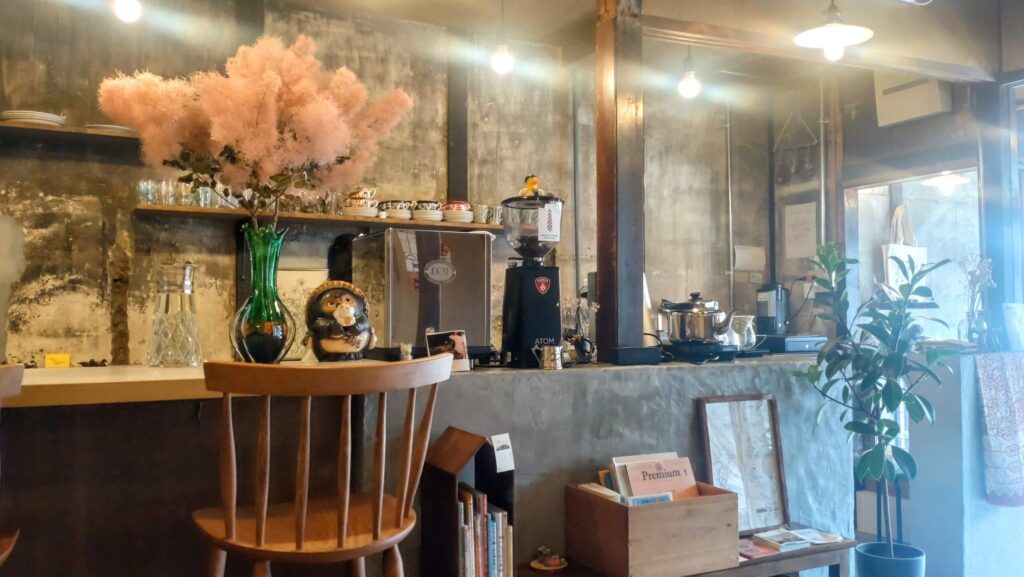 ネクタイコーヒーの店内カウンター。レトロな照明と木製家具、カウンター上のたぬきの置物やピンクの花が印象的な落ち着いた空間