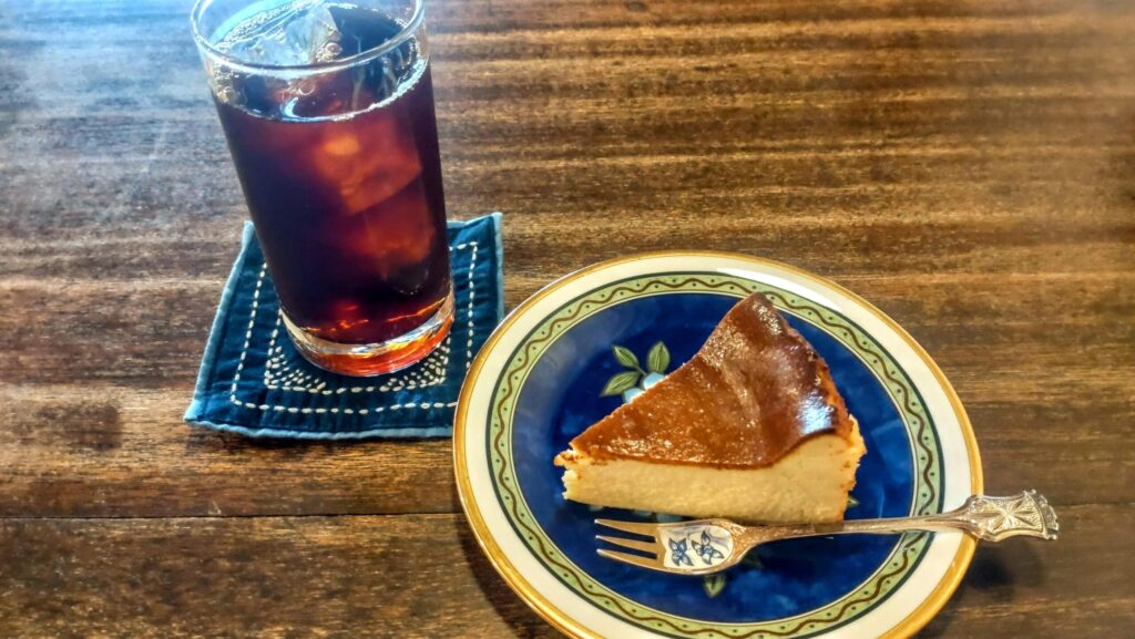 ネクタイコーヒーのアイスコーヒーと自家製チーズケーキ。器やカトラリーにもこだわりが感じられる。